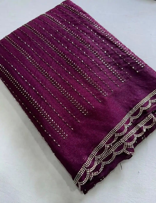 A close-up of a deep purple fabric, likely a saree body or dupatta, decorated with vertical rows of metallic silver sequins and a scalloped border of silver beads and sequins.