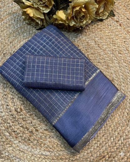 Blue fabric with grid pattern and embroidered edge on a textured surface