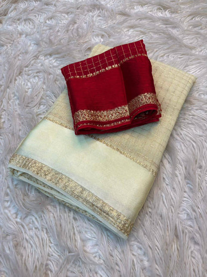 Red and gold saree on a light green fabric with gold border on a textured white background