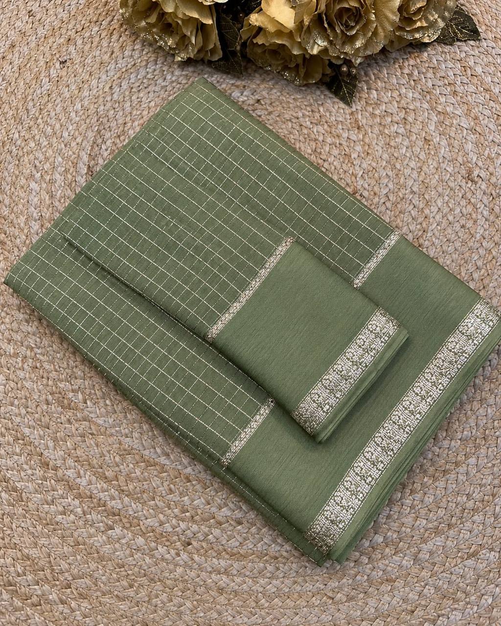 Green fabric with grid pattern and decorative trim on a textured surface