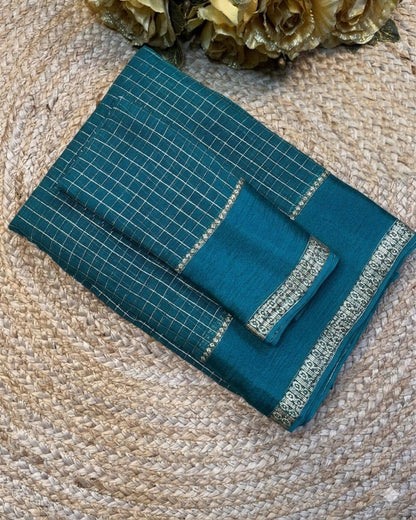 Teal saree with silver border on a textured surface