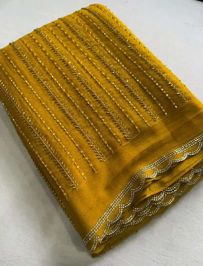 A folded mustard yellow fabric piece with vertical metallic gold embroidery and a scalloped embroidered border.