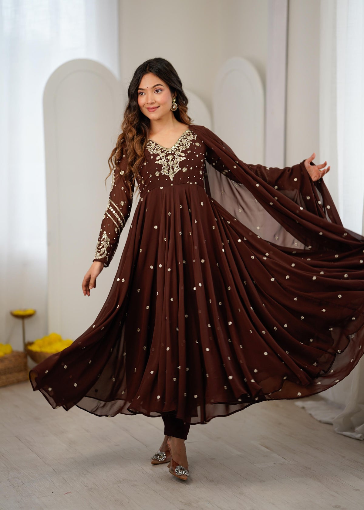 Model twirling in a brown sequin embroidered Anarkali gown with dupatta