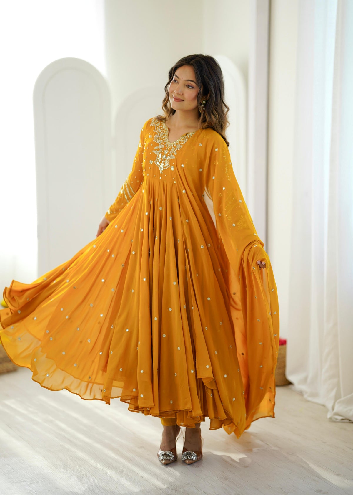 Model twirling in a mustard yellow sequin embroidered Anarkali gown with dupatta