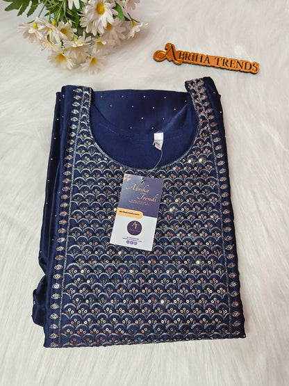 A folded navy blue embroidered kurta set with metallic gold and silver scalloped patterns, displayed on a white faux fur background with a 'Abriha Trends' wooden badge and white flowers.