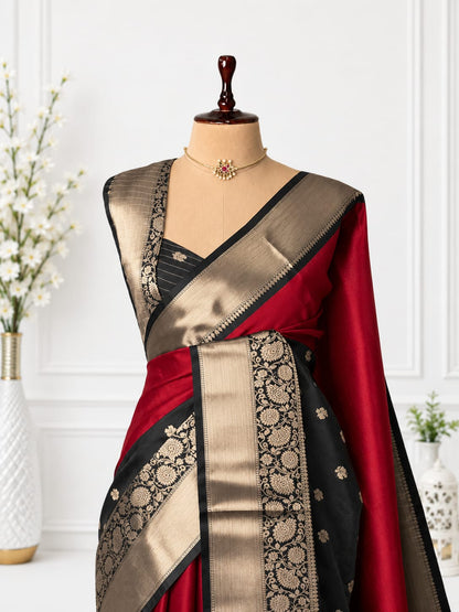 A black and deep red silk saree with intricate gold zari brocade work, displayed on a mannequin torso with a matching gold necklace.