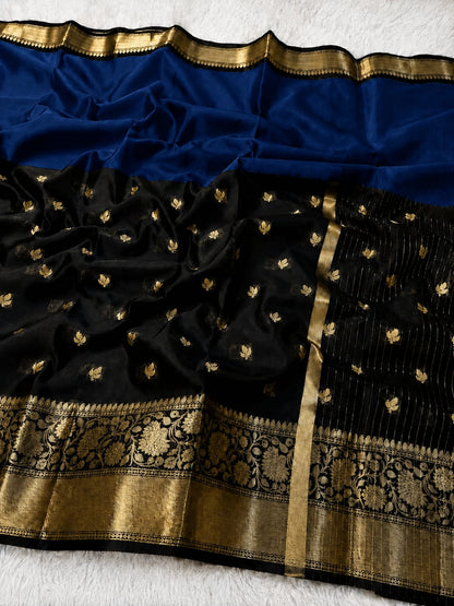 Black silk Banarasi saree with gold zari embroidery, a wide blue border, and a detailed gold brocade pallu, laid flat on a white textured background.