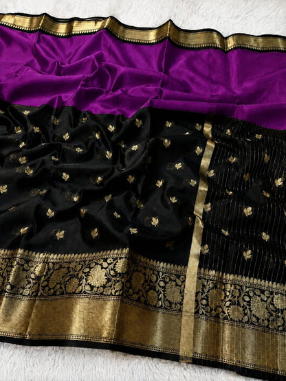 A black silk saree with a vibrant purple border and a wide gold zari brocade pallu, laid flat on a white textured surface.