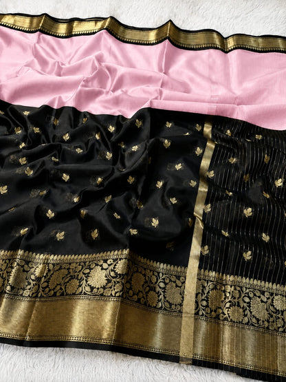 A black silk saree with a pink border, decorated with small gold floral motifs and featuring an ornate gold zari border.