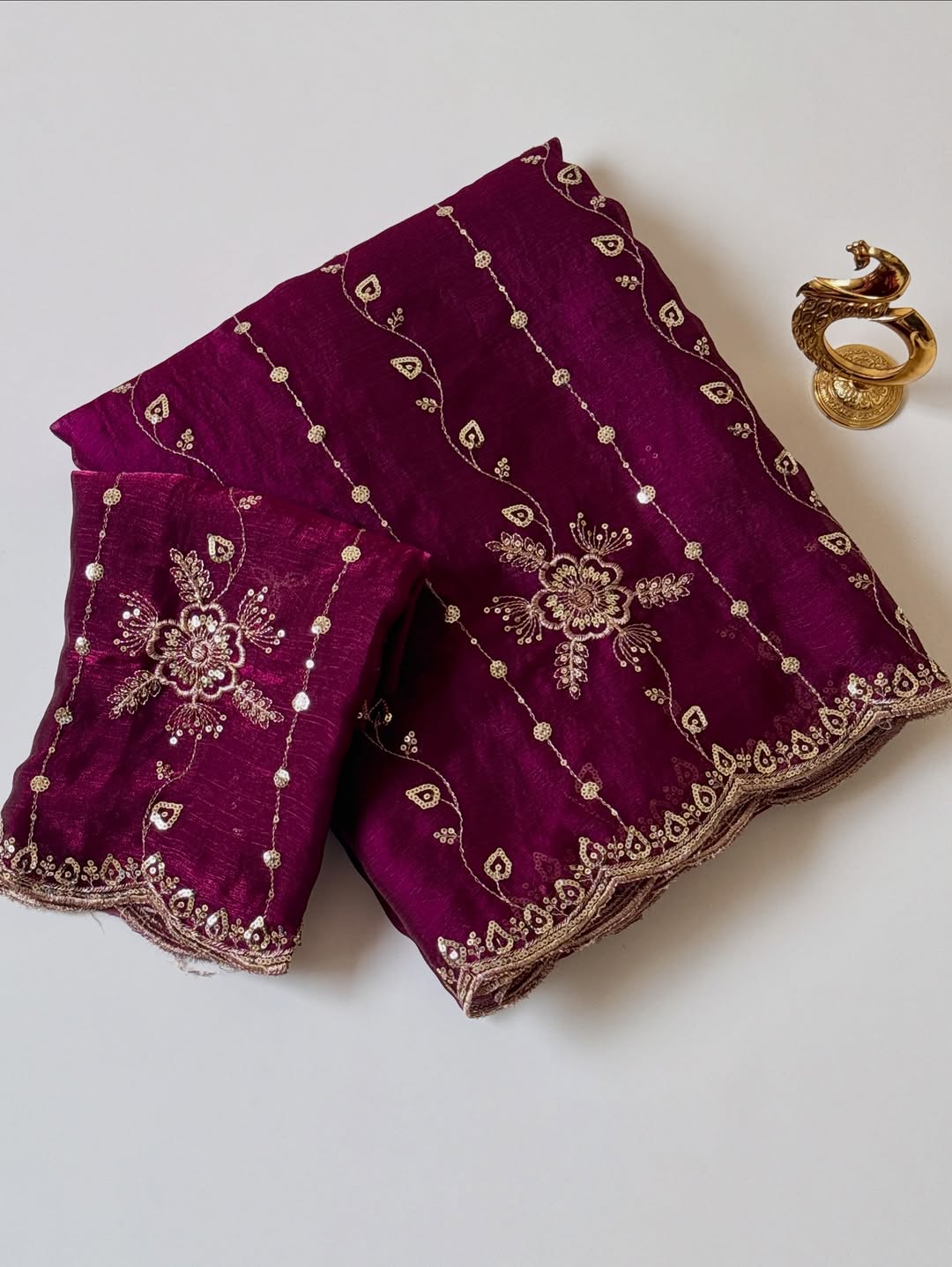 Wine Fendy chiffon saree with gold sequin embroidery and scalloped border, folded with blouse piece