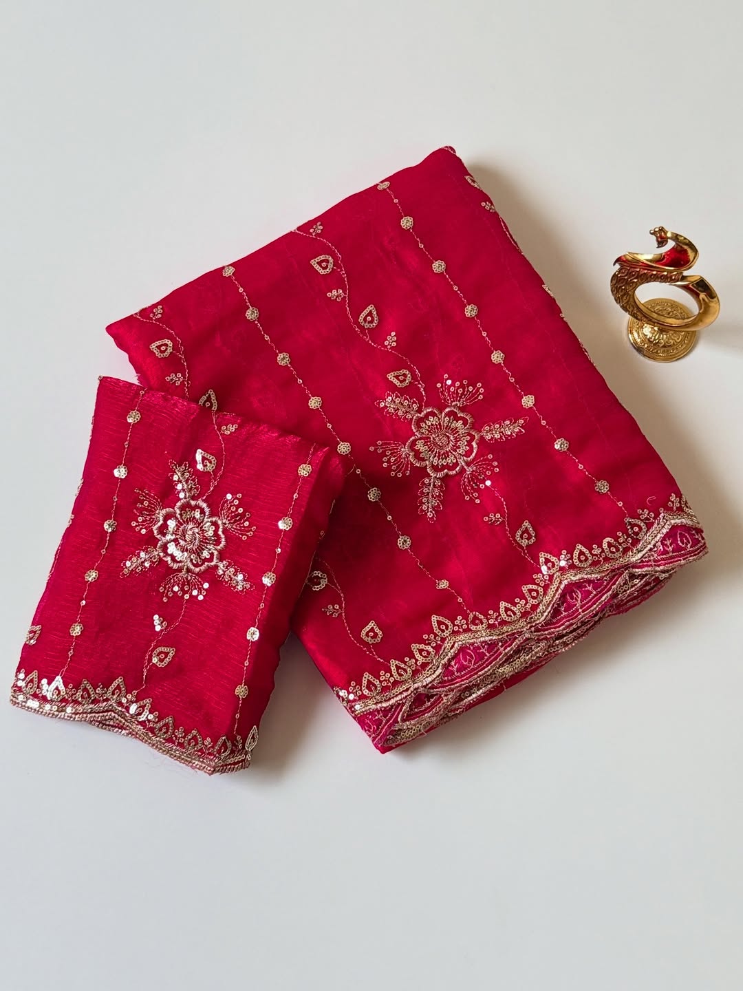 Rani pink Fendy chiffon saree with gold sequin embroidery and scalloped border, folded with blouse piece