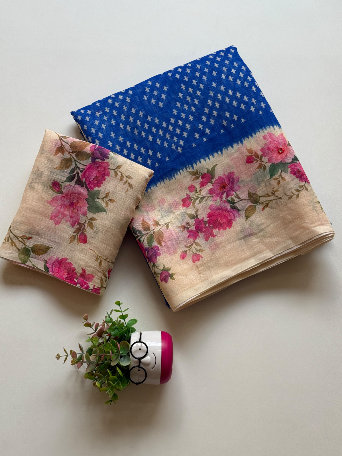 Royal blue linen cotton saree with white cross-motif print and floral digital print border, folded with printed blouse piece