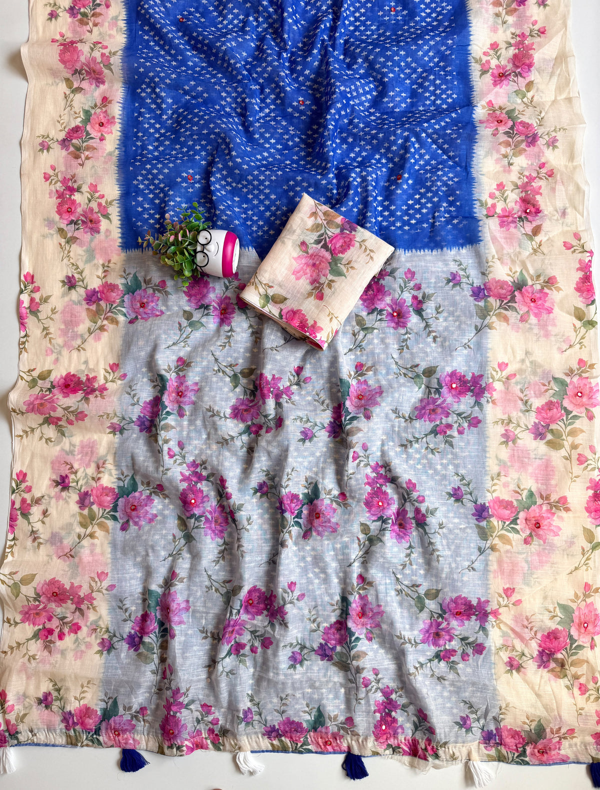 Royal blue linen cotton saree spread out showing grey-blue floral pallu with mirror work and blue and white tassels