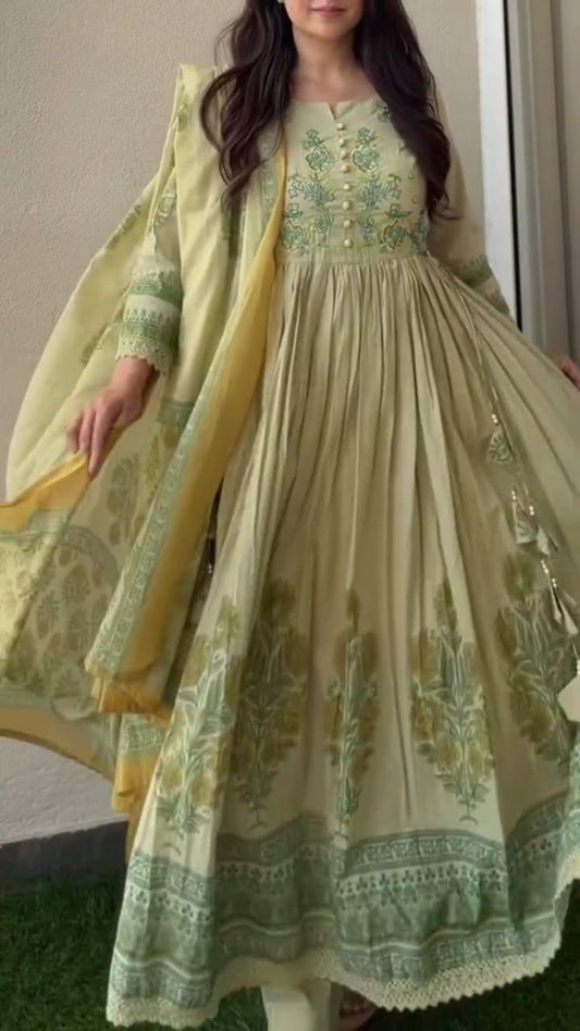 Woman wearing pista green pure cotton Anarkali with embroidered button yoke, floral print flare and lace hem, draped with mustard-bordered dupatta