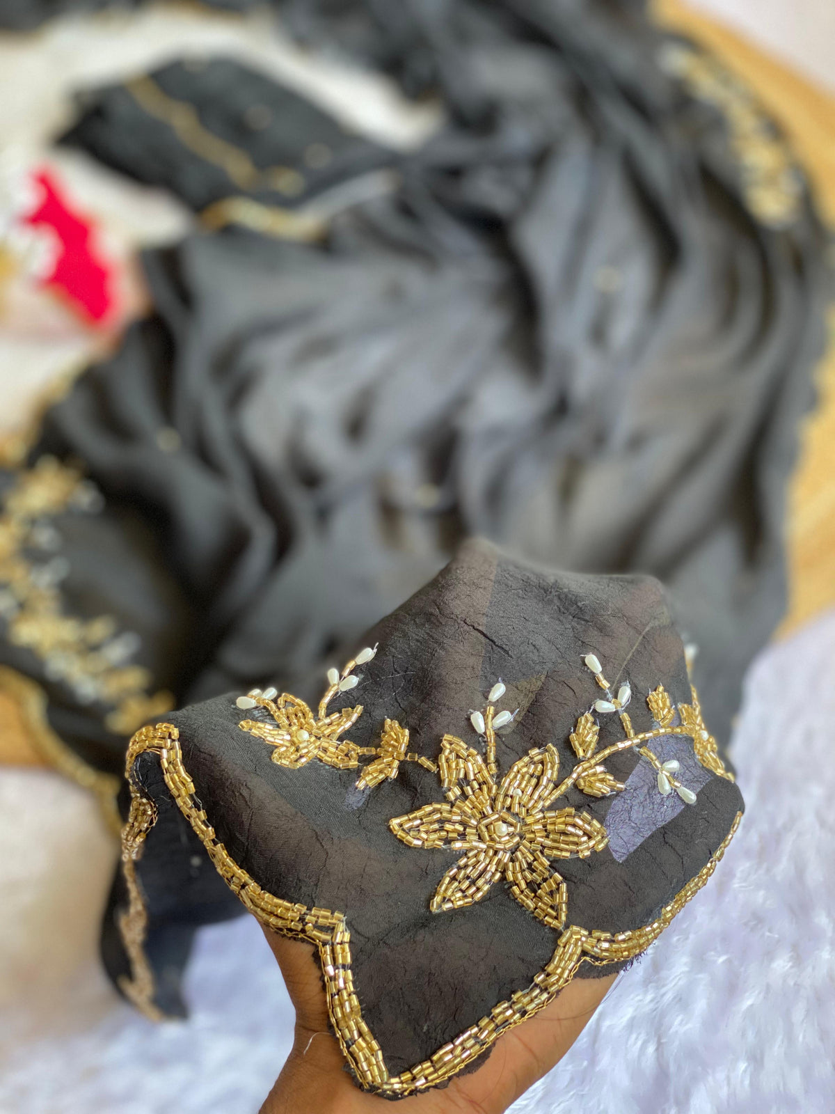 Close-up of gold tube bead and pearl drop floral handwork on Black crush silk saree with scalloped bead edge