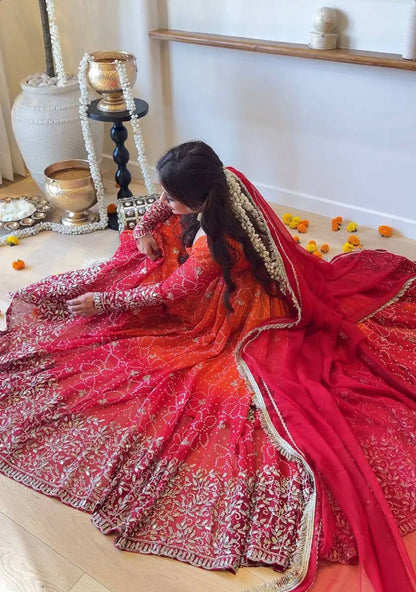 Seated model with Anarkali flare spread showing gold sequin embroidery on hem and sleeves