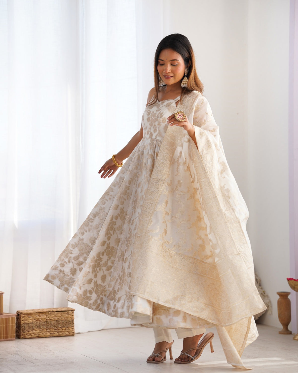 Model twirling in ivory Anarkali gown showing flared kali cut skirt and pant