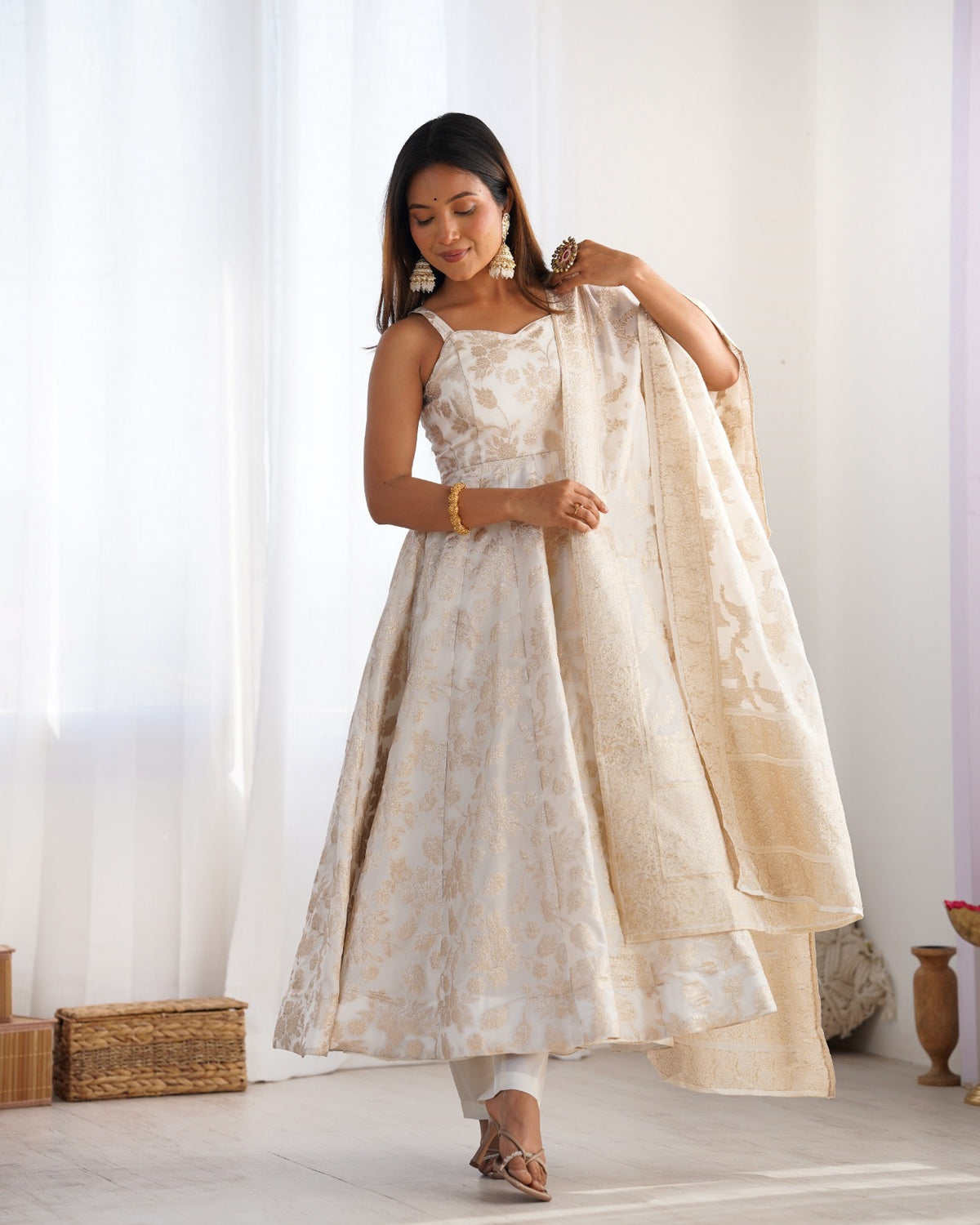 Full-length ivory and gold Anarkali gown with dupatta over one shoulder