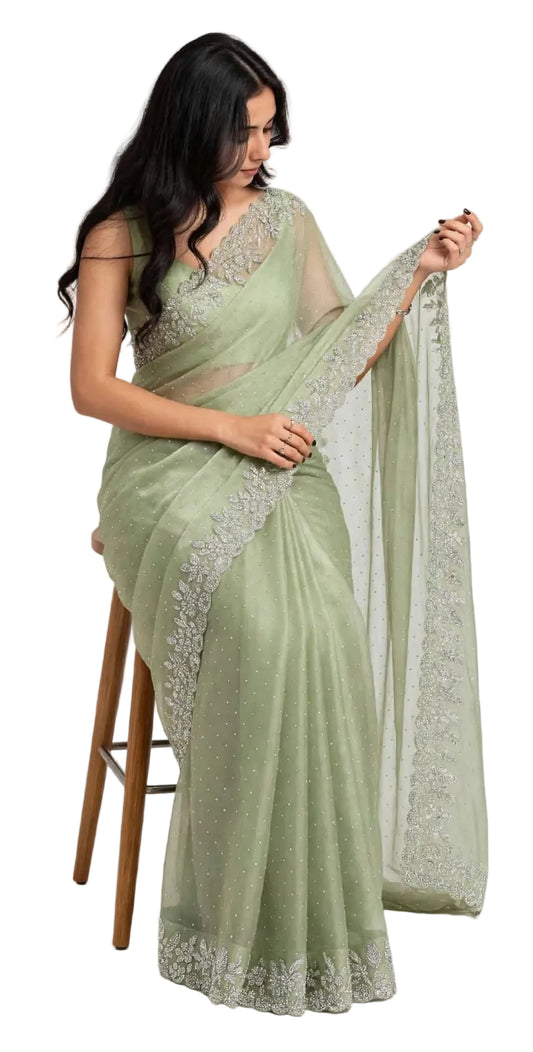 Seated model in the sage green space silk saree, showing the stone dotted body and floral stone border along the pleats