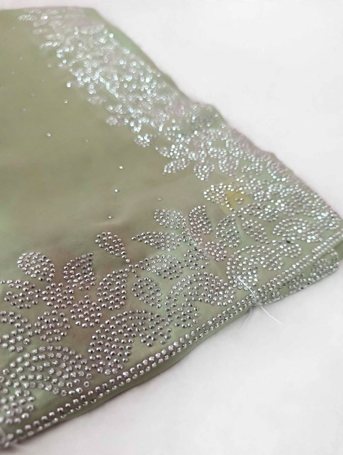 Close-up of the silver floral leaf stone border on sage green space silk