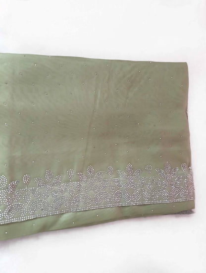Folded sage green saree showing scattered silver stones and the floral leaf stone border