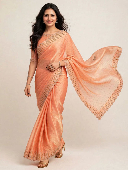 Model walking in an orange space silk saree with stone work, the pallu flowing out to show its scalloped stone and bead border